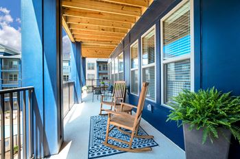A porch with blue walls and a wooden rocking chair
